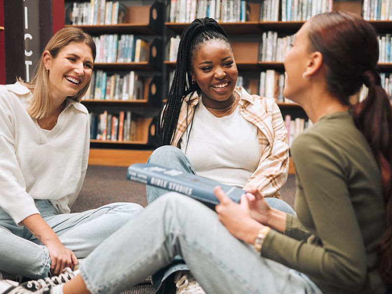 Tre kvinder taler sammen i et bibliotek